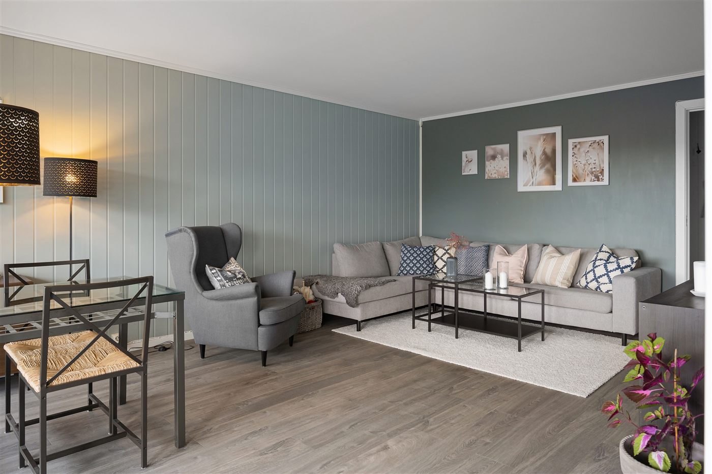 Wohnzimmer mit zweifarbig gestrichener Wand aus Paneel- und Wandfarbe, abgestimmt auf Sofa und Bildergalerie