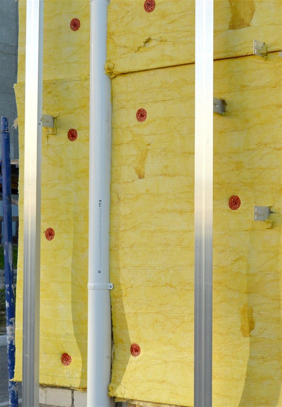 Frisch montierte Mineralwoll-Dämmplatten einer Fassade mit Tellerdübeln und Aluminium-Anschlussprofilen vor dem Fassadenanstrich
